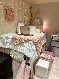 a laptop computer sitting on top of a bed in a room with pink and white decor