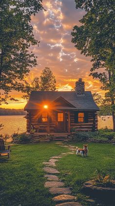 a log cabin sits on the edge of a lake as the sun sets behind it