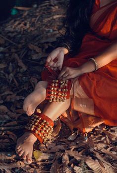 a woman sitting on the ground with her feet covered in beads and bracelets,