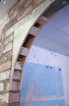 an arch in the side of a brick building that is being built with blue paint