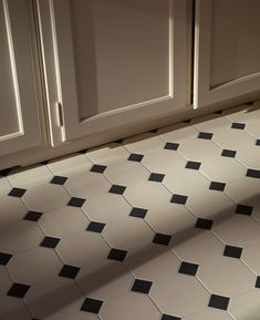 a black and white checkered tile floor in a kitchen with cupboards behind it