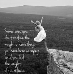 a woman standing on the edge of a cliff with her arms in the air while she is