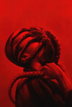 a woman wearing a red hat with braids on her head, in front of a red background