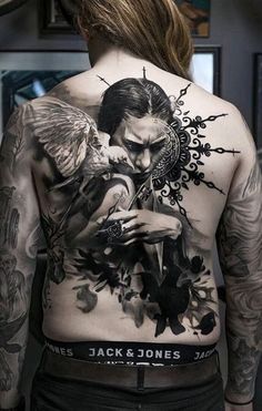 the back of a man with tattoos on his chest and arms, holding a knife