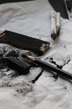 two pencils are laying on top of some black and white paper next to an eraser