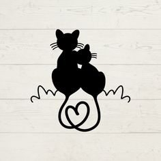 a black cat sitting on top of a wooden floor next to a heart shaped object