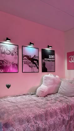 a bedroom with pink walls and posters on the wall