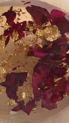 some gold and red leaves in a white bowl