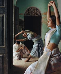 two women are dancing in an old building with one woman holding her arm up to the side