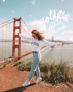 a woman is dancing in front of the golden gate bridge with her arms spread out