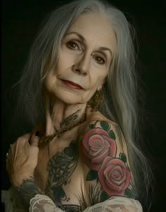 an older woman with grey hair and tattoos on her chest, posing for the camera