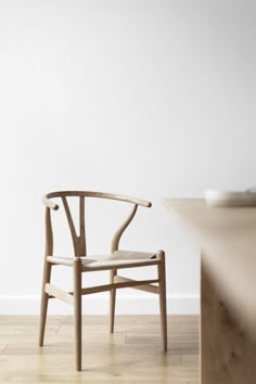 a wooden chair sitting on top of a hard wood floor next to a white wall