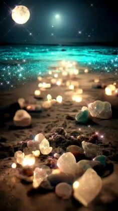 the beach is filled with candles and stars in the night sky, as if it were floating