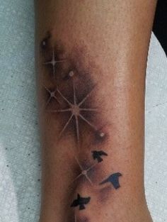 a tattoo on the leg of a woman with three birds flying in the night sky