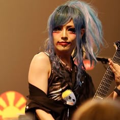 a woman with blue hair holding a guitar