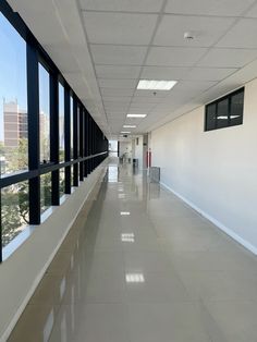 an empty hallway with lots of windows on both sides and no people in the room