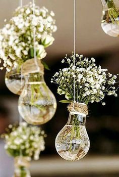 three hanging vases filled with flowers and small white flowers are suspended from the ceiling