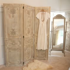 an antique white wardrobe and mirror in a room