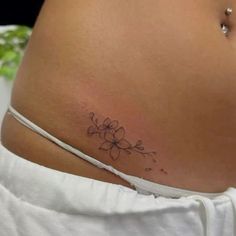 a woman's stomach with a small flower tattoo on the side of her belly