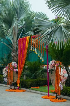 an outdoor wedding setup with orange and pink flowers on the ground, palm trees in the background