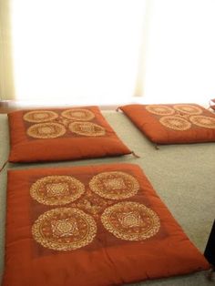 four orange pillows sitting on the floor in front of a window