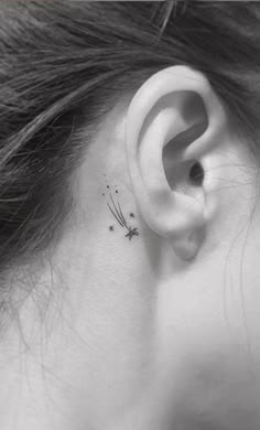 a woman's ear with a small dragonfly tattoo on her left behind the ear