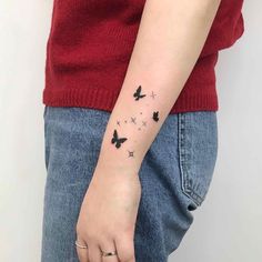 a woman's arm with black butterflies on the left side of her wrist and stars in