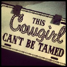 this cowgirl can't be tamed sign hanging on the wall in front of a door