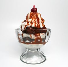 an ice cream sundae in a glass bowl with chocolate sauce and cherries on top