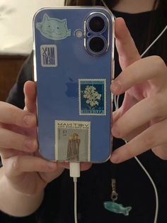 a person holding up a cell phone with some stickers on it's back