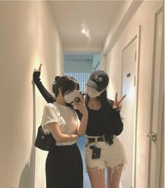 two young women are taking pictures in the hallway