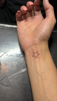 a woman's hand with a small star tattoo on it