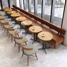 a row of tables sitting next to each other on top of a tiled floor in front of large windows