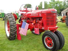an old red farmall tractor with american flag on it's front and side