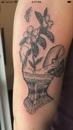 a woman's arm with a tattoo on it and flowers growing out of the vase