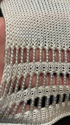someone is holding their hand with some beading on the side of it and there are other beads in the middle of the stitch