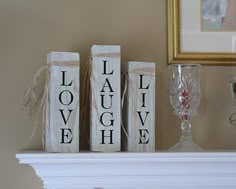 two wooden blocks that say love and laugh on top of a table next to a wine glass