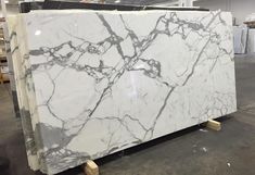 a large white marble slab with black veining on the top and sides, in a warehouse