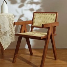 a white vase sitting on top of a wooden chair next to a lace covered table cloth