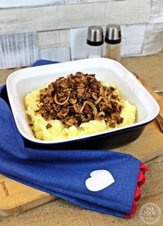a white bowl filled with food on top of a wooden cutting board