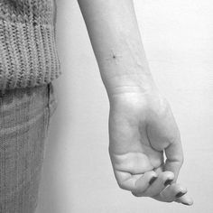black and white photograph of a woman's arm with a tiny star tattoo on it