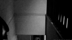 a blurry image of a person walking down the stairs in a dark room with white walls