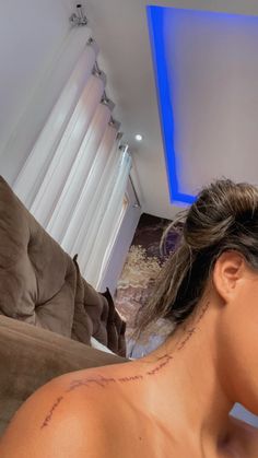 a woman with a tattoo on her neck sitting in a living room next to a couch