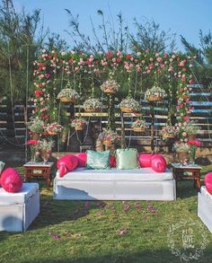 an outdoor seating area with pink and green flowers on the wall, white couches
