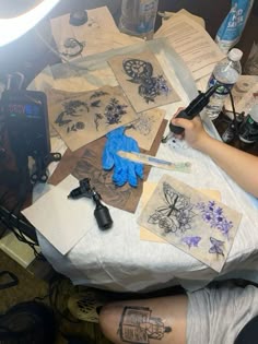 a person sitting at a table with some tattoos on it's legs and blue gloves