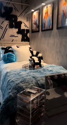 a bed sitting in a bedroom next to two pictures on the wall and a table