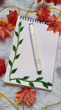 a notepad with leaves and a pen on it