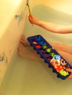 a person sitting in a bathtub holding a paintbrush and painting on the wall