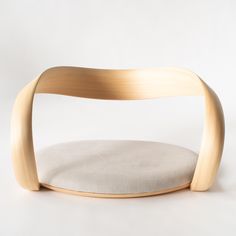 a wooden chair sitting on top of a white floor next to a pillow in front of it
