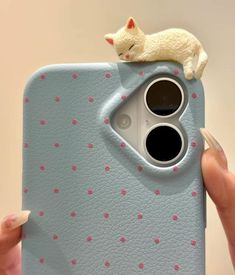 a person holding up a cell phone case with a cat sitting on top of it